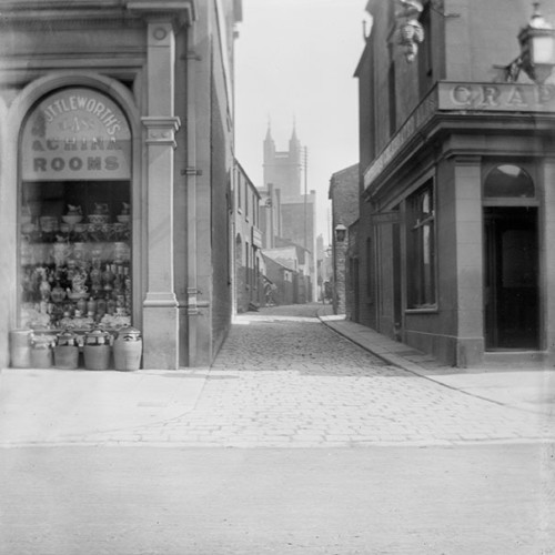 Street scene including shop window for 'Shuttleworth's China Rooms.'