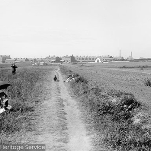 Children in fields alongside road with town in distance
