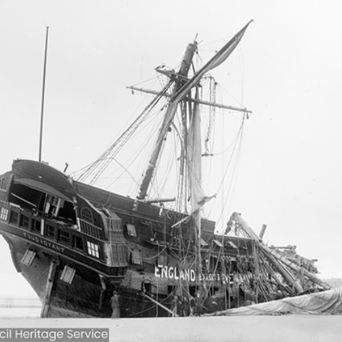 Sailing ship wrecked on beach with 'England Expects...' graffiti.