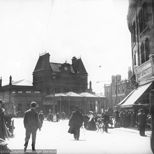 Crowds in street scene, shop sign reads 'Clarke & Heap - Beef Department.'