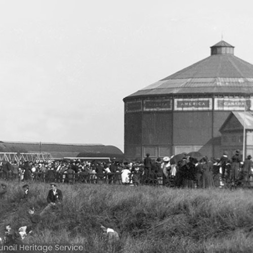 Crowds in front of octagonal shaped wooden building