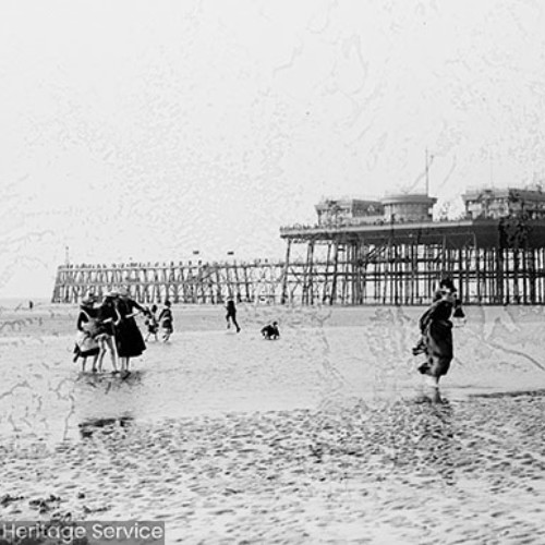 People on the beach in front of Blackpool North Pier
