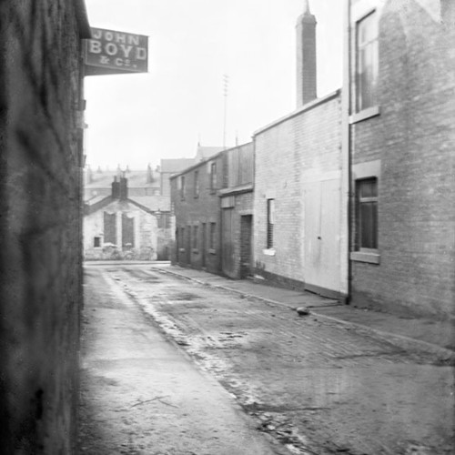 Street scene with sign above building reading 'John Boyd & Co.'