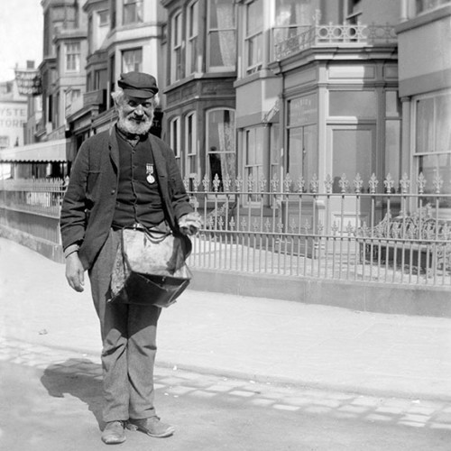 Old man with beard standing in street