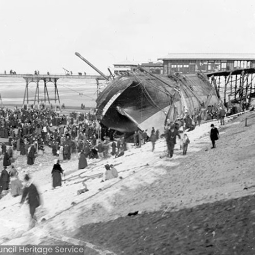 Crowds on beach in front of shipwreck
