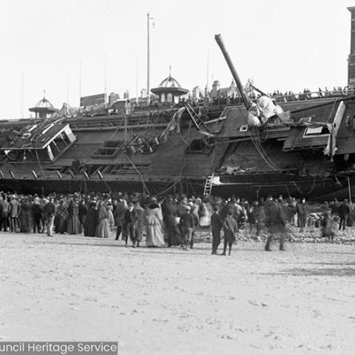 Crowds on beach in front of shipwreck