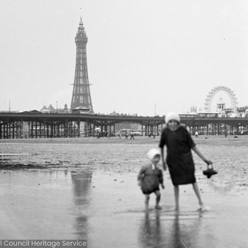 Woman and child playing on beach with Blackpool Tower in background