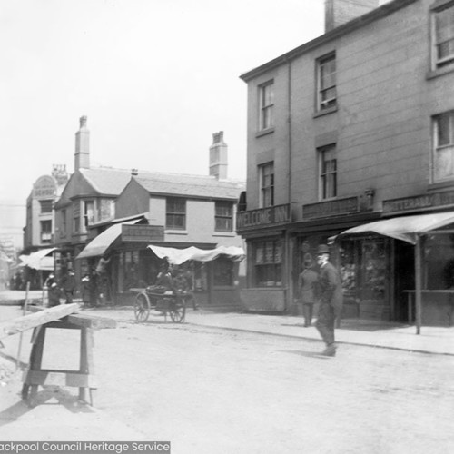 Street scene in front of inn with sign reading 'Welcome Inn'