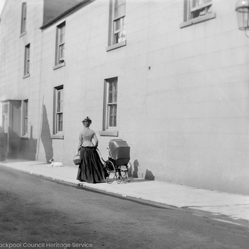 A woman pushing a pram down the street