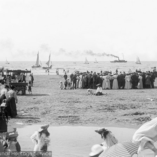 Crowds on the beach watching boats