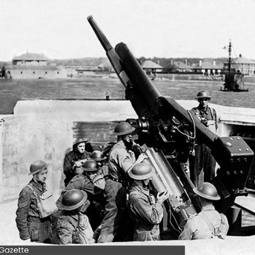 Anti-aircraft gun pointing towards the sky, with a number of soldiers surrounding the base of it.