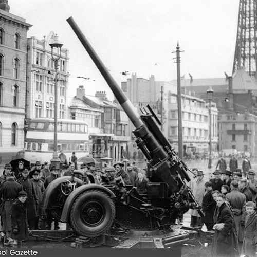 People surrounding an anti-aircraft gun which is pointing towards the sky.