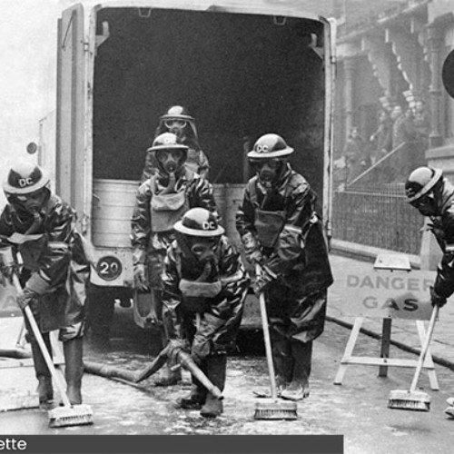 Eight people, wearing gas masks and protective clothing.