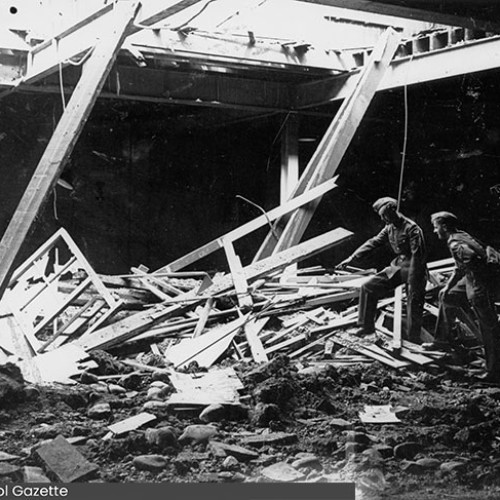 Two people looking at debris on the floor from the hole in the roof above.