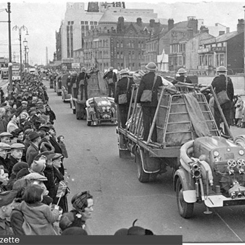 Parade of Civil Defence vehicles driving down the Promenade, with onlookers lining the pavements either side.