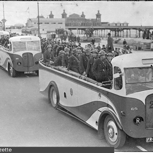 Line of open top vehicles driving down the Promenade, carrying Civil Defence members.