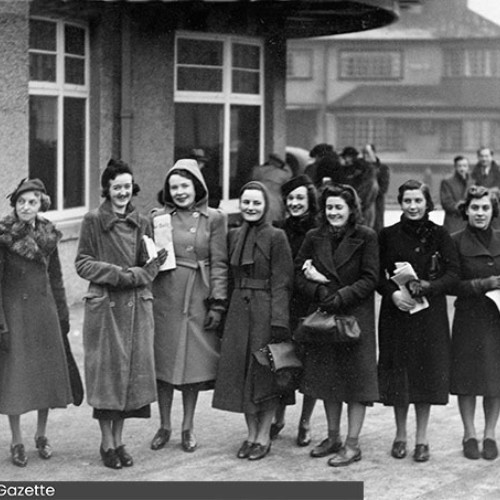 Group of ten women stood in a line outside of the building.