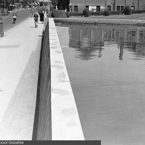 Large open tank of water to the side of the road.