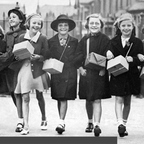 Group of ten schoolgirls walking in a line, each carrying their gas mask box.
