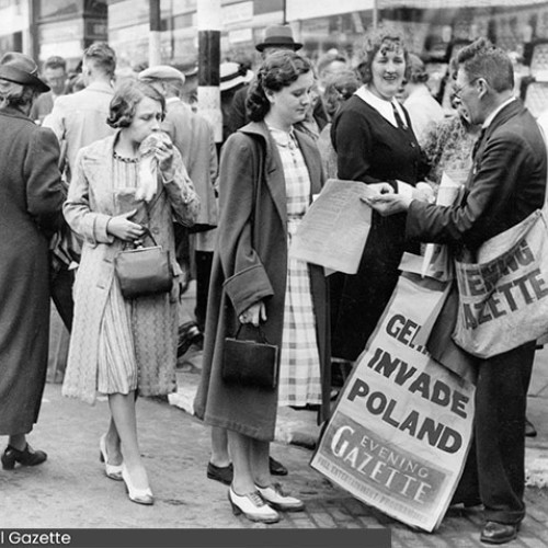 Newspaper seller with an Evening Gazette bag over his shoulder and a sign saying Germans Invade Poland.