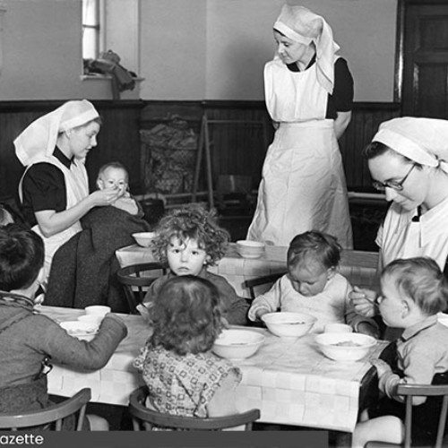 Group of three Sisters in a room with a group of small children who are eating.