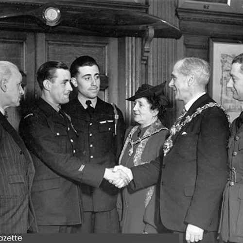 Group of six people, with the Mayor shaking the hand of one of the airmen.