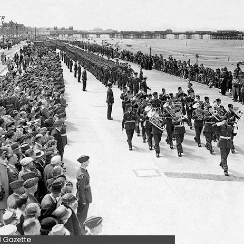 Spectators lining the Promenade on either side of a parade of marching RAF and band.