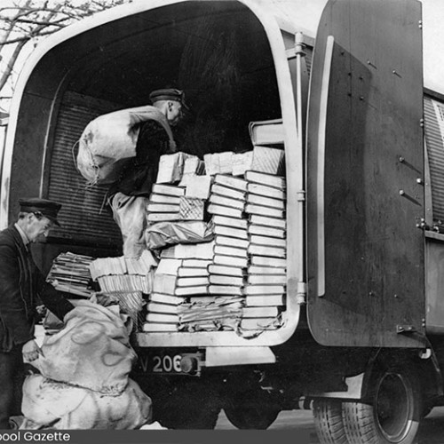 Two workers taking sacks of paper into a van. On the side of the van, a sign reads This Week and Every Week Salvage is Essential.