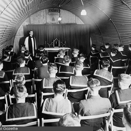 Group of Sea Cadets sat down looking towards a Priest and an altar.