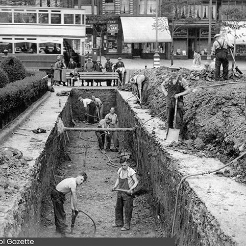 Workers digging a large hole in preparation for an air raid shelter.