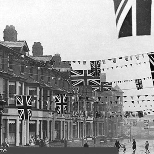 Union Jack flag bunting stretched across the street with people below it.