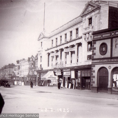 Street scene of hotel and shops with Blackpool Tower in background.