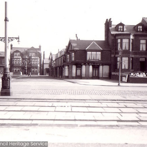 Street view  of various apartment buildings, guest houses and a pub in background. .