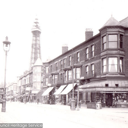 Street scene with a parade of shops and Blackpool Tower in the background.