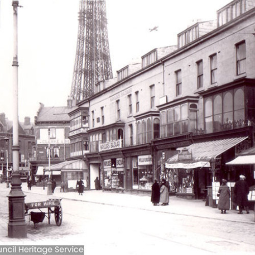 Street scene with parade of shops and Blackpool Tower in background.