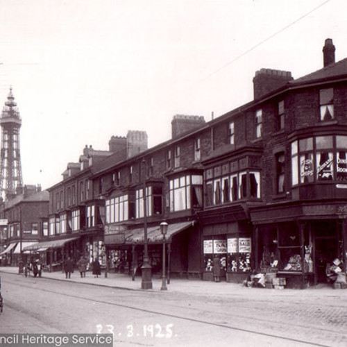 Street scene with a parade of shops and Blackpool Tower in the background.