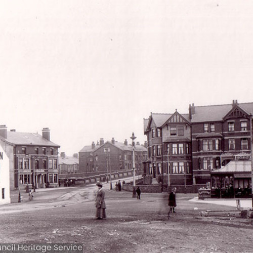 A street scene with Inn buildings, houses and a refreshment kiosk.