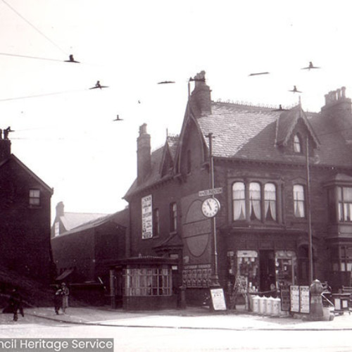 Street scene with shops and a tram shelter.