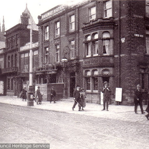 Street scene of pedestrians walking past hotel building.