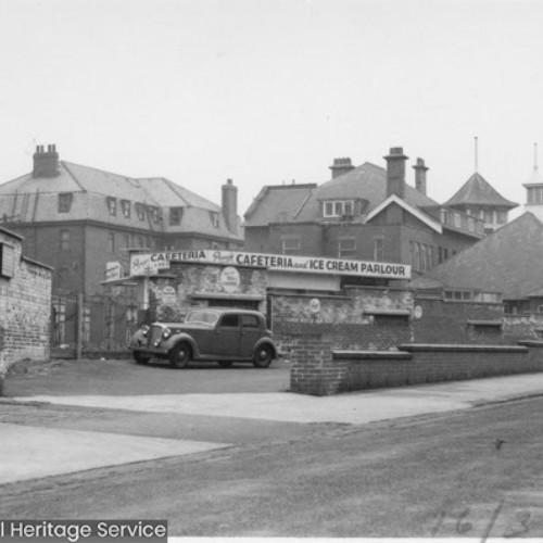 Exterior of the side and rear of Uncle Toms Cabin. There is a Cafeteria and Ice Cream Parlour advertised.