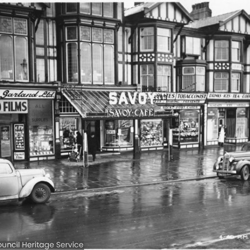 Shop fronts, including Burton and Garland Ltd Selo Films, the Savoy Cafe and souvenir shops.