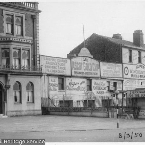 Exterior of the New Inn & Central Hotel on the left, with an Amusements Park to the right advertising games to play.