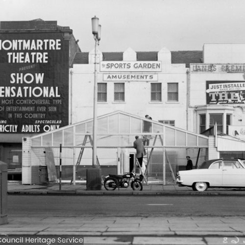 Exterior of three buildings. From left to right is the Montmartre Theatre advertising Show Sensational, The Sports Garden Amusements and Lanes Premier Amusements.