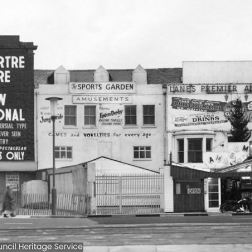 Exterior of three buildings, from left to right is Montmartre Theatre Present Show Sensational, The Most Controversial Type Of Entertainment Ever Seen In This Country, Daring Spectacular, Strictly Adults Only, The Sports Garden Amusements and Lanes Premier Amusements.