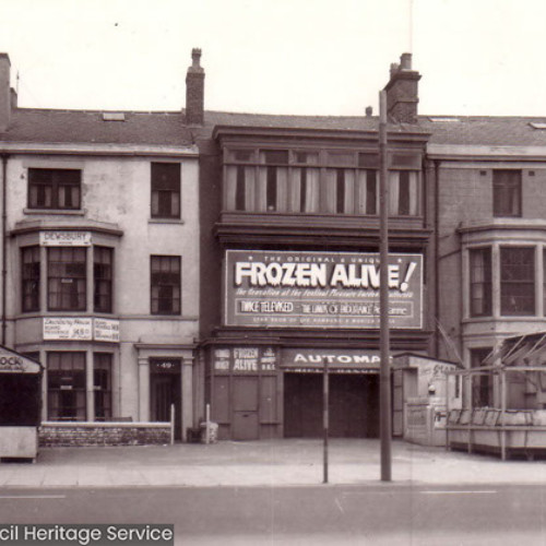 Row of buildings with one advertising Frozen Alive!