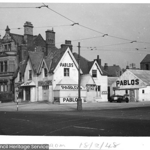 Street corner, with building on the corner trading as Pablo's advertising Fish and Chips and Ice Cream Cottage.