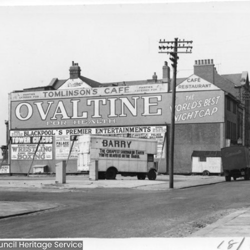 Side wall of Tomlinson's Cafe, with a large advertisement for Ovaltine. On the land next to the cafe is a small lorry parked up.