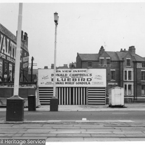 Temporary building next to Tomlinson's Cafe, advertising that Donald Campbell's Bluebird is on display inside.