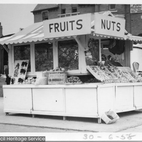 Stall selling fruits and nuts and a man stood next to the stall.