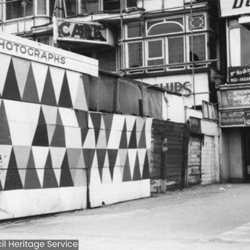 Closed gifts, refreshments and photograph stalls on the forecourt in front of a row of buildings.